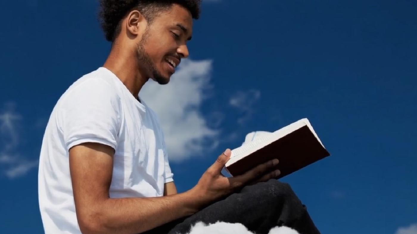 Young Man Reading Book on Cloud Surreal Scene